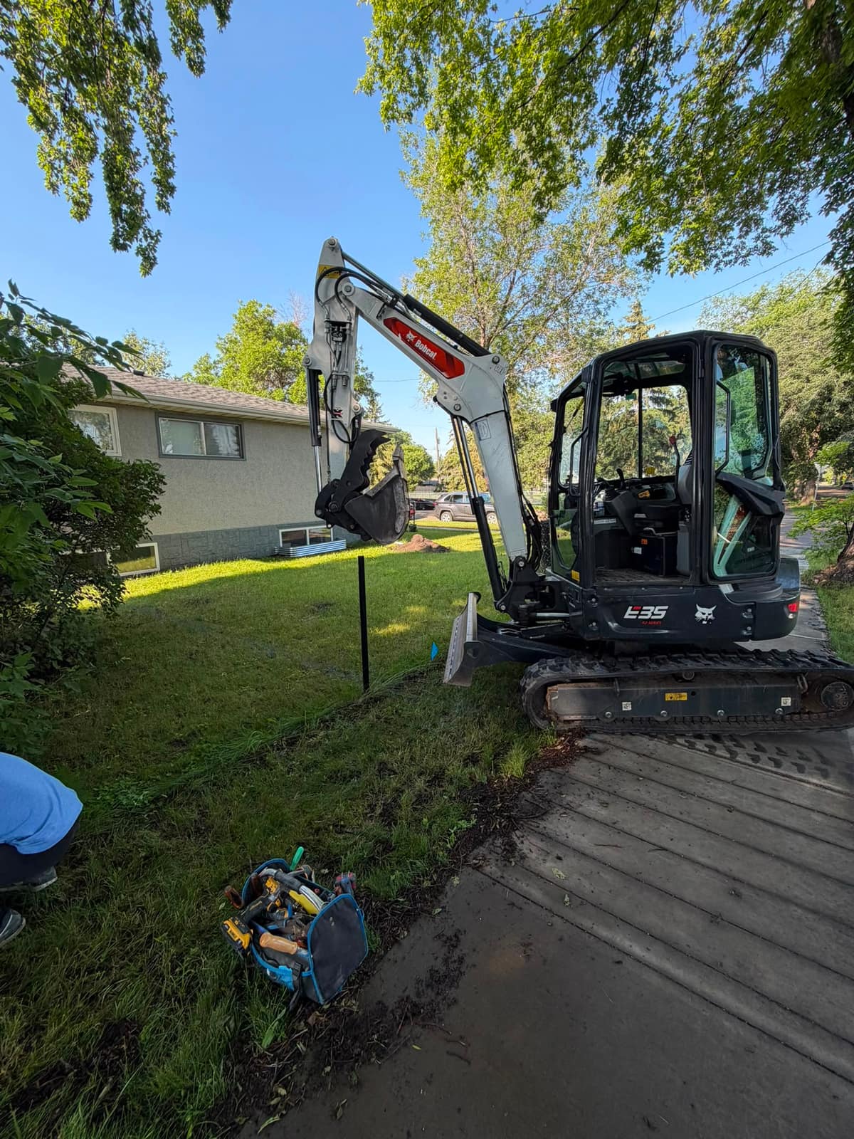 Bobcat E35 mini excavator digging in a residential front yard